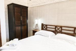 a bedroom with a white bed and a wooden cabinet at Villa Adele Eleganza & Comfort in Pachino