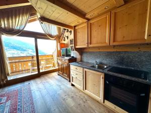 a kitchen with wooden cabinets and a large window at Alpine Escape 4 in Bormio