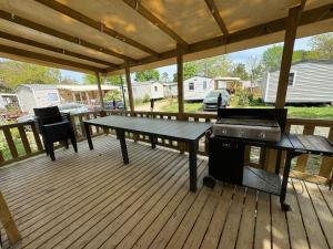 eine abgeschirmte Veranda mit einem Picknicktisch und einem Grill in der Unterkunft Un toit sur le bassin Bungalow solaire in Lège-Cap-Ferret