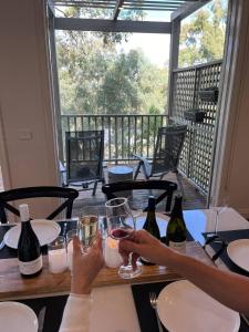 a person sitting at a table with two glasses of wine at Villa Above Par, Privately Managed within Cypress Lakes Resort, Premier 2 Storey Villa, 2 Bedrooms, both with Private Ensuites, Light Breakfast included in Pokolbin +44 photos