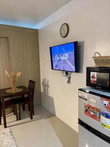 a living room with a tv on the wall and a table at Shell Residences MOA by Kirstie in Manila