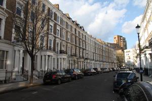 eine Straße mit Autos, die an der Seite eines Gebäudes geparkt sind in der Unterkunft Exhibition Court Hotel 4 in London