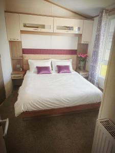 a bedroom with a large bed with two purple pillows at Modern caravan Robin Hood Rhyl in Rhyl
