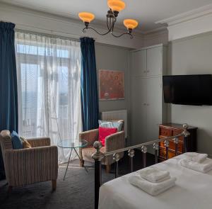 Un dormitorio con una cama y sillas y una ventana. en The White Rock Hotel, en Hastings