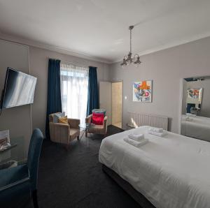 a hotel room with a bed and a bathroom at The White Rock Hotel in Hastings +5 photos