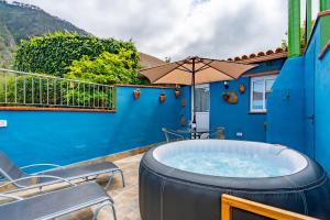 a hot tub on a patio with chairs and an umbrella at Casa Rural La Resbala - Casa Bejeque in La Orotava