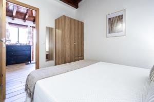 a bedroom with a white bed and a wooden cabinet at Casa Rural La Resbala - Casa Cardon in La Orotava