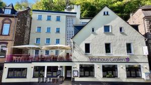 a white building with tables and umbrellas in front of it at Weinhaus Gräfen in Cochem