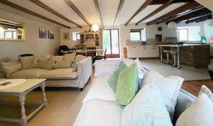 a living room with white couches and a kitchen at Emerald Coast Gites and Lodge in Hénansal