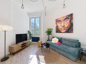 a living room with a blue couch and a painting at Charmant 2P Juan-les-Pins in Antibes
