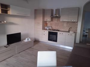 a kitchen with white cabinets and a flat screen tv at Casa Rosa Forio d'Ischia in Forio d'Ischia