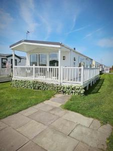 a white house with a white fence and a yard at Lyons robin hood lodge Rhyl in Rhyl