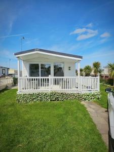 a small white house with a white fence at Lyons robin hood lodge Rhyl in Rhyl