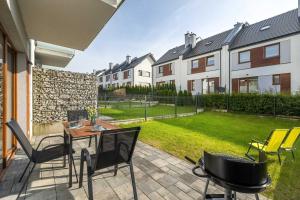 a patio with a table and chairs in a yard at Spacious House Kołobrzeg with Garden Grill and Parking by Noclegi Renters in Niekanin