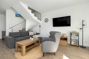 a living room with a couch and a table at Spacious House Kołobrzeg with Garden Grill and Parking by Noclegi Renters in Niekanin