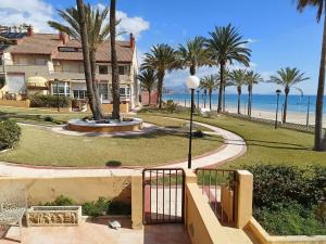 a walkway to a house with palm trees and the beach at Bungalow primera línea de playa in El Campello