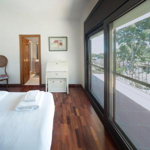 a bedroom with a white bed and a large window at Villa espectacular privada con piscina y AACC in Castelldefels