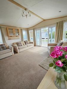 a living room with couches and a vase of pink roses at Luxury lodge lyons robin hood in Rhyl