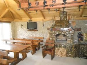 a room with a fireplace and wooden tables and benches at Sadyba Lileya in Verkhovyna