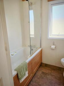 a bathroom with a tub and a sink and a window at Luxury lodge lyons robin hood in Rhyl +16 photos
