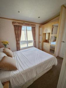 a bedroom with a large white bed and a window at Luxury lodge lyons robin hood in Rhyl