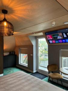 a room with a tv on the wall and a chair at Boetiekhotel Het Huis in Fluitenberg