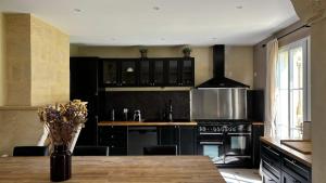 a kitchen with black cabinets and a wooden table at Maison au coeur des vignes in Puisseguin