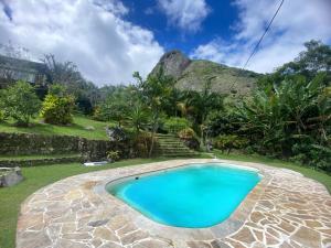 a swimming pool in a garden with a mountain in the background at Sítio com piscina em São Pedro da Serra in São Pedro da Serra