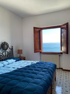 a bedroom with a blue bed and a large window at Casa Il Panorama in Praiano
