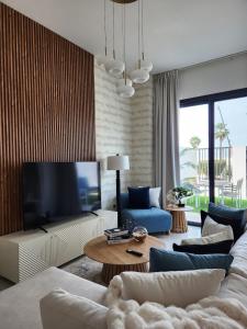 Una sala de estar con un sofá blanco y un televisor. en Nasma Luxury Stays - Lakeside Retreat Stylish & Cozy Villa Stay, en Ras al Khaimah