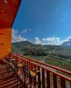 a wooden deck with tables and chairs on top of a mountain at Tower Hill Cabin Dieng in Diyeng