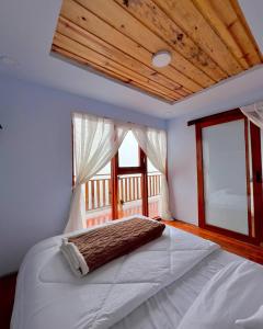 a bedroom with a white bed with a window at Tower Hill Cabin Dieng in Diyeng