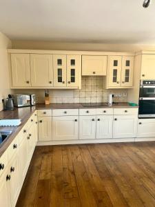 a kitchen with white cabinets and a wooden floor at Clianba- 3 bedroom Highland home from home in Spean Bridge