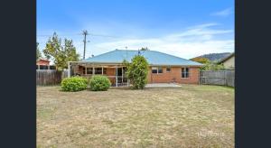 ein rotes Backsteinhaus mit einem Zaun und einem Hof in der Unterkunft Bridgecroft Bungalow in Richmond