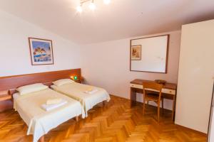 Un dormitorio con dos camas y un escritorio y una mesa. en Villa Nila, a charming villa just a short walk away from the beach, en Premantura
