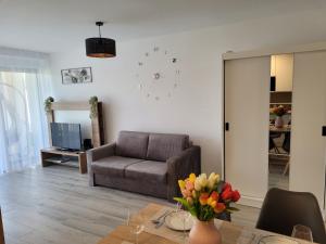 a living room with a couch and a table with flowers at Aura Residence Apartman in Sárvár