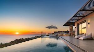 an infinity pool in a house with a sunset at Nimbus Villas in Kalamitsi