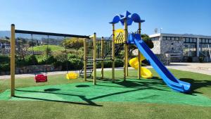 a playground with a blue and yellow slide at BeachfrontSunset Apartment in Bahçeli