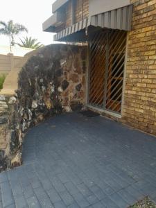 a building with a stone wall and a patio at TANS Garden Cottage in Centurion +8 photos