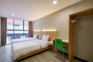 a hotel room with two beds and a desk and a green chair at Gaia Realty Homestay, Private & Convenient Stay in Georgetown in George Town
