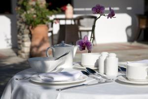 a table with a white table cloth with silverware and purple flowers at Despotiko in Portaria