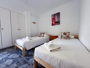 two beds in a room with white walls at El Delfín in Playa de las Americas
