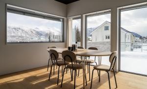 a dining room with a table and chairs and large windows at North Estate City House in Tromsø