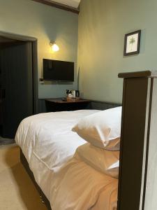a bedroom with a white bed and a television at The Plume of Feathers in Farnham