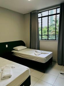 two beds in a room with a window at Belô Home & Office in Belo Horizonte