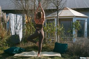 Eine Frau, die im Garten eine Yoga-Pose einnimmt. in der Unterkunft DE BUITENKANS urban camping - unique cabins in Rotterdam