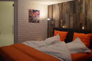 1 cama con almohadas de color naranja y blanco y una pintura en Les Chambres d'Elza, en Mouscron