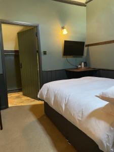 a bedroom with a bed and a flat screen tv at The Plume of Feathers in Farnham
