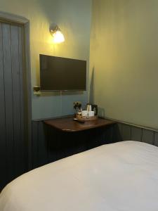 a bedroom with a bed and a tv on the wall at The Plume of Feathers in Farnham