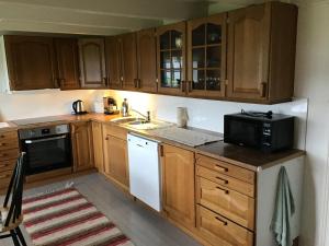 a kitchen with wooden cabinets and a microwave at Gamlemgarden by Norgesbooking - house by the sea in Longva +9 photos